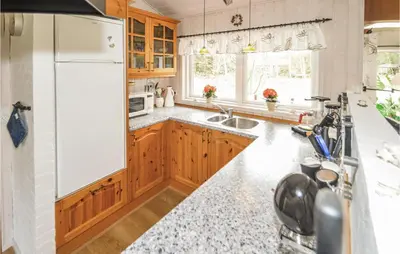 a kitchen with wooden cabinets and a white refrigerator at Holiday Home Brovst With A Fireplace 03 in Brovst