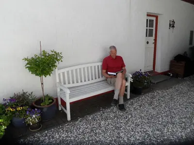 a man sitting on a bench next to a building at Tvillinggaard Thy in Vang