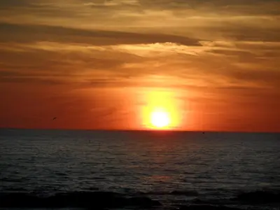 a sunset over the ocean with the sun in the sky at Tvillinggaard Thy in Vang