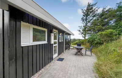 a black house with a patio and a table at Holiday Home Blokhus With Fireplace 05 in Blokhus
