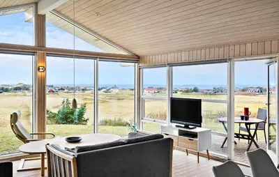 a living room with a television and a table with chairs at Holiday Home Blokhus With Fireplace 05 in Blokhus
