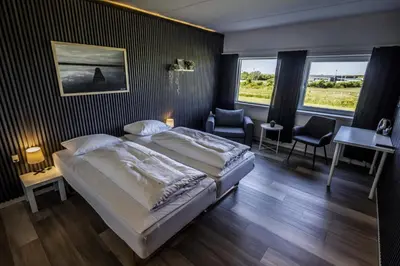 a bedroom with two beds and a desk and windows at Løgstør Parkhotel in Løgstør