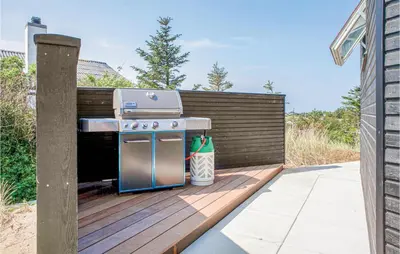 a barbecue grill on a deck with a fence at Holiday Home Blokhus With Hot Tub Iv in Blokhus