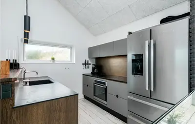 a kitchen with a stainless steel refrigerator and a sink at Holiday Home Blokhus With Hot Tub Iv in Blokhus