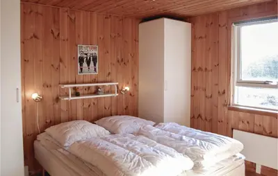 a bed in a room with a wooden wall at Holiday Home Pandrup With Hot Tub V in Pandrup