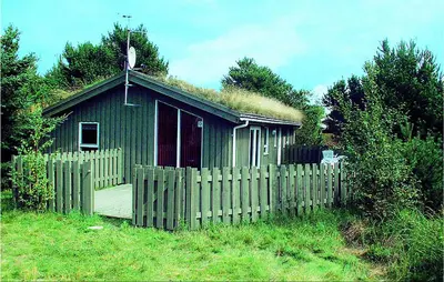 a small house with a grass roof with a fence at Holiday Home Pandrup With Hot Tub V in Pandrup