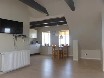 a living room with a kitchen and a table and chairs at Harboøre Hotel in Harboør