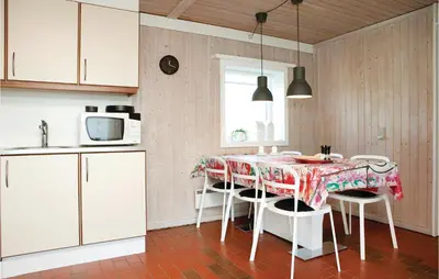 a kitchen with a table with chairs and a microwave at Holiday Home Pandrup With Fireplace Ii in Pandrup