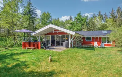 a red house with a picnic table in a yard at Holiday Home Hurup Thy With Hot Tub I in Sønder Ydby