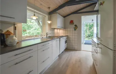a kitchen with white cabinets and a large window at Holiday Home Hurup Thy With Hot Tub I in Sønder Ydby