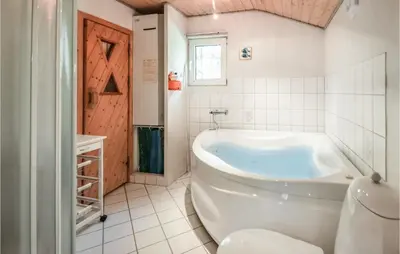 a white bathroom with a tub and a window at Holiday Home Hurup Thy With Hot Tub I in Sønder Ydby