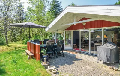 a patio with chairs and an umbrella on a house at Holiday Home Hurup Thy With Hot Tub I in Sønder Ydby