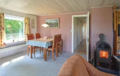 a dining room with a table and a wood stove at Holiday Home Veslos With Fireplace I in Højstrup