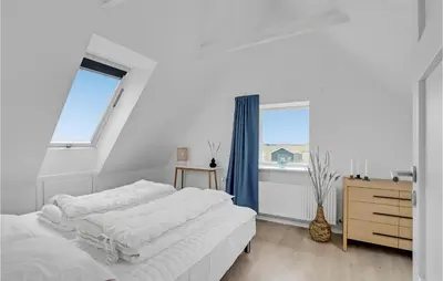a white bedroom with two beds and a window at Klitrosen in Harboør