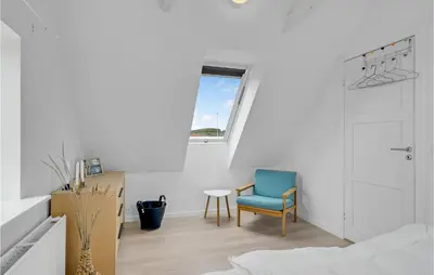 a white room with a blue chair and a window at Klitrosen in Harboør