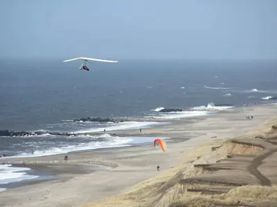 a plane flying over a beach with people flying kites at 6 person holiday home in Lemvig-By Traum in Ferring