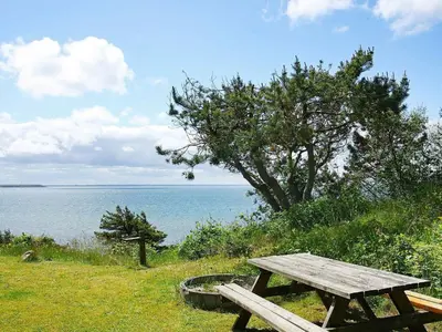 a wooden picnic table sitting on the grass near the water at Secluded Beach Retreat - By Traum Ferienwohnungen in Lihme