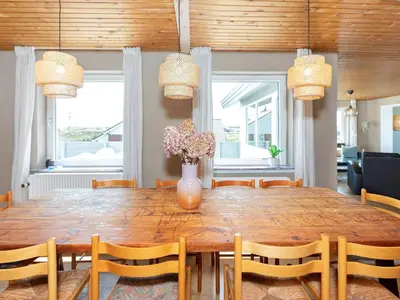 a dining room table with chairs and a vase with flowers at 8 person holiday home in Frøstrup-By Traum in Lild Strand