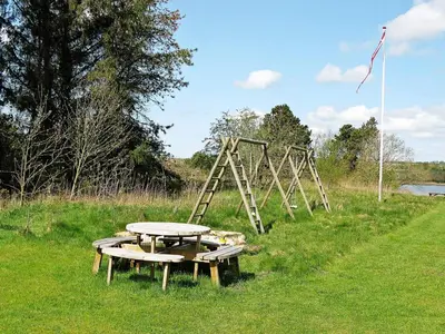 a picnic table and a swing set in a field at 10 person holiday home in Højslev-By Traum in Lund