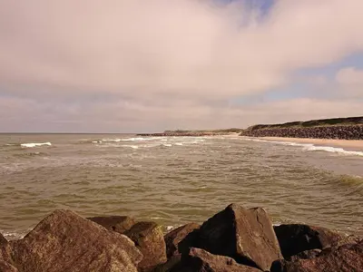 a beach with rocks and the ocean with waves at 8 person holiday home in Løgstør-By Traum in Trend