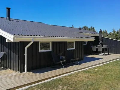 a house with a deck with two chairs and a table at 9 person holiday home in Løkken-By Traum in Grønhøj