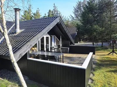 a house with a deck with a table and chairs at 6 person holiday home in Saltum-By Traum in Saltum