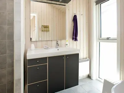 a bathroom with a sink and a mirror at Bright Beach House Retreat - By Traum Ferienwohnungen in Trudslev