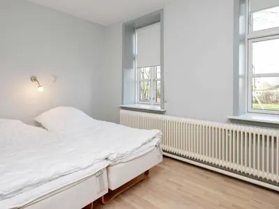 a white bedroom with a bed and two windows at 26 person holiday home in Roslev-By Traum in Åsted