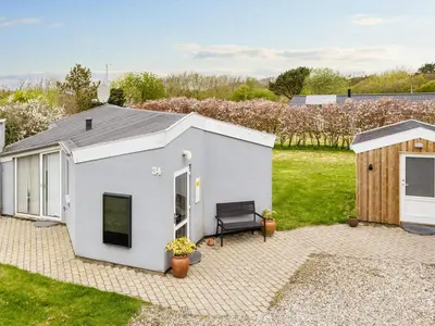a white shed with a bench in a yard at 6 person holiday home in Vestervig-By Traum in Vestervig