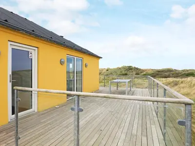 a boardwalk leading to a yellow building with a door at Luxury Seaside Retreat - By Traum Ferienwohnungen in Tranum Strand