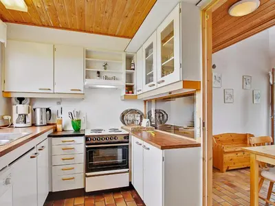 a kitchen with white cabinets and a wooden ceiling at Luxury Retreat with Pool - By Traum Ferienwohnungen in Hvalpsund