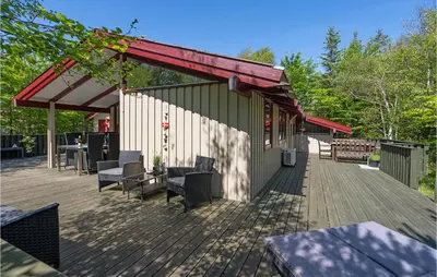a deck with chairs and tables and a building at Holiday Home Saltum Doggerbanke in Saltum