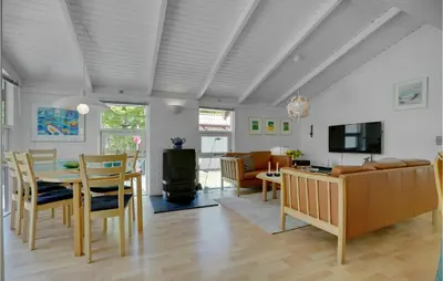 a dining room and living room with a table and chairs at Holiday Home Saltum Doggerbanke in Saltum