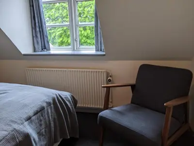 a bedroom with a bed and a chair and a window at Sevel Kro in Vinderup