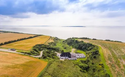 an aerial view of a house on a hill next to the water at Næsbydale Badehotel in Ranum