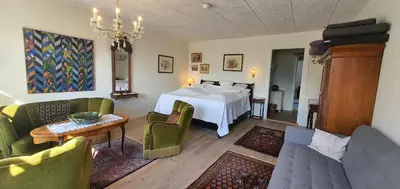 a bedroom with a bed and a table and chairs at Næsbydale Badehotel in Ranum