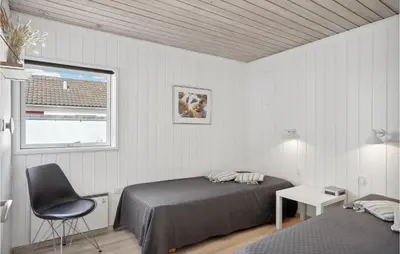 a bedroom with a bed and a chair and a window at Two-Bedroom Holiday Home In Pandrup in Pandrup