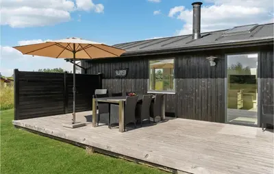 a wooden deck with a table and an umbrella at Three-Bedroom Holiday Home In Thisted in Nørre Vorupør
