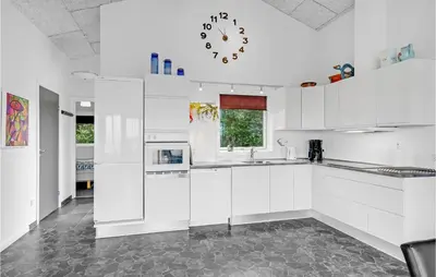 a kitchen with white cabinets and a clock on the wall at Three-Bedroom Holiday Home In Skals in Skals