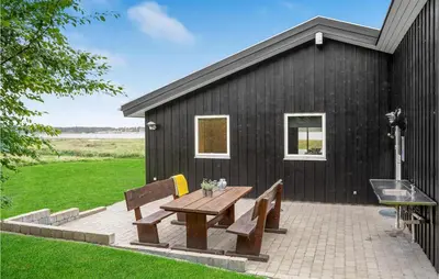 a picnic table and two benches in front of a black building at Three-Bedroom Holiday Home In Skals in Skals