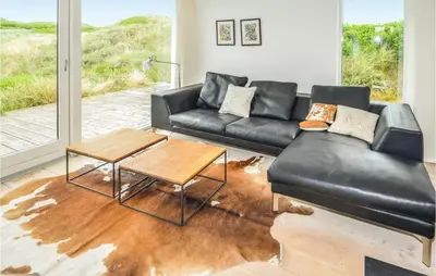 a living room with a leather couch and a table at Stunning Home In Løkken With Kitchen in Løkken