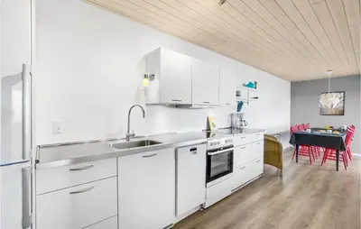 a white kitchen with white cabinets and a table at Three-Bedroom Holiday Home In Farso in Farsø