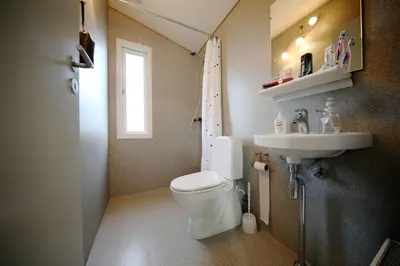 a bathroom with a toilet and a sink at Tangsø Hytteby in Bækmarksbro