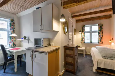 a small room with a bed and a kitchen with a microwave at Viborg City Rooms in Viborg
