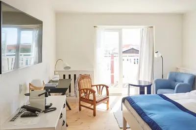 a bedroom with a bed and a desk with a computer at Strandhotellet in Blokhus