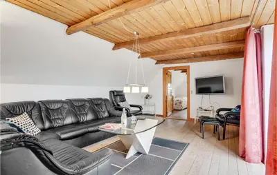 a living room with a black leather couch and a table at Bakkegården in Thisted