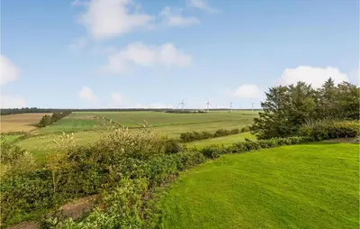 a green field with wind turbines in the distance at Bakkegården in Thisted
