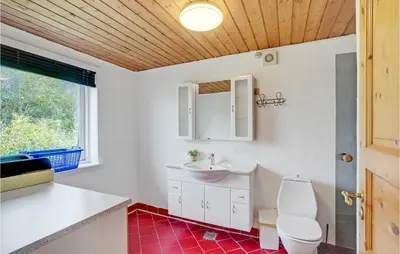a bathroom with a sink and a toilet and a window at Bakkegården in Thisted