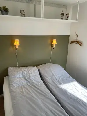 a bed in a bedroom with two lights on the wall at Stenbjerg Kro & Badehotel in Snedsted