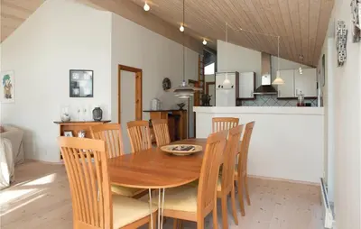 a dining room and kitchen with a wooden table and chairs at Three-Bedroom Holiday Home In Blokhus in Blokhus
